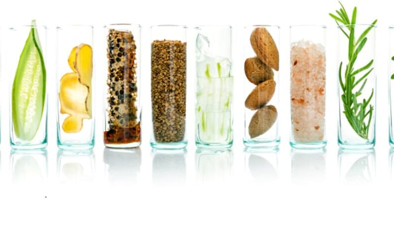 Glass jars of whole, recognisable ingredients: ginger, seeds, almonds and herbs