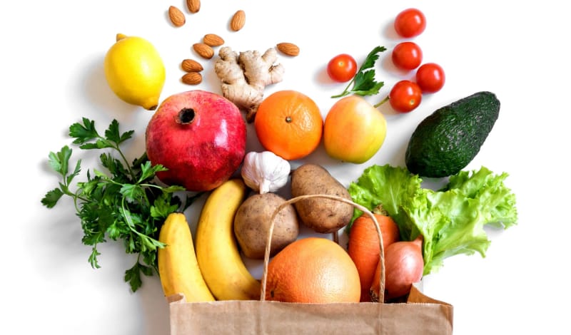 Fresh fruit and vegetables spilling from a paper bag